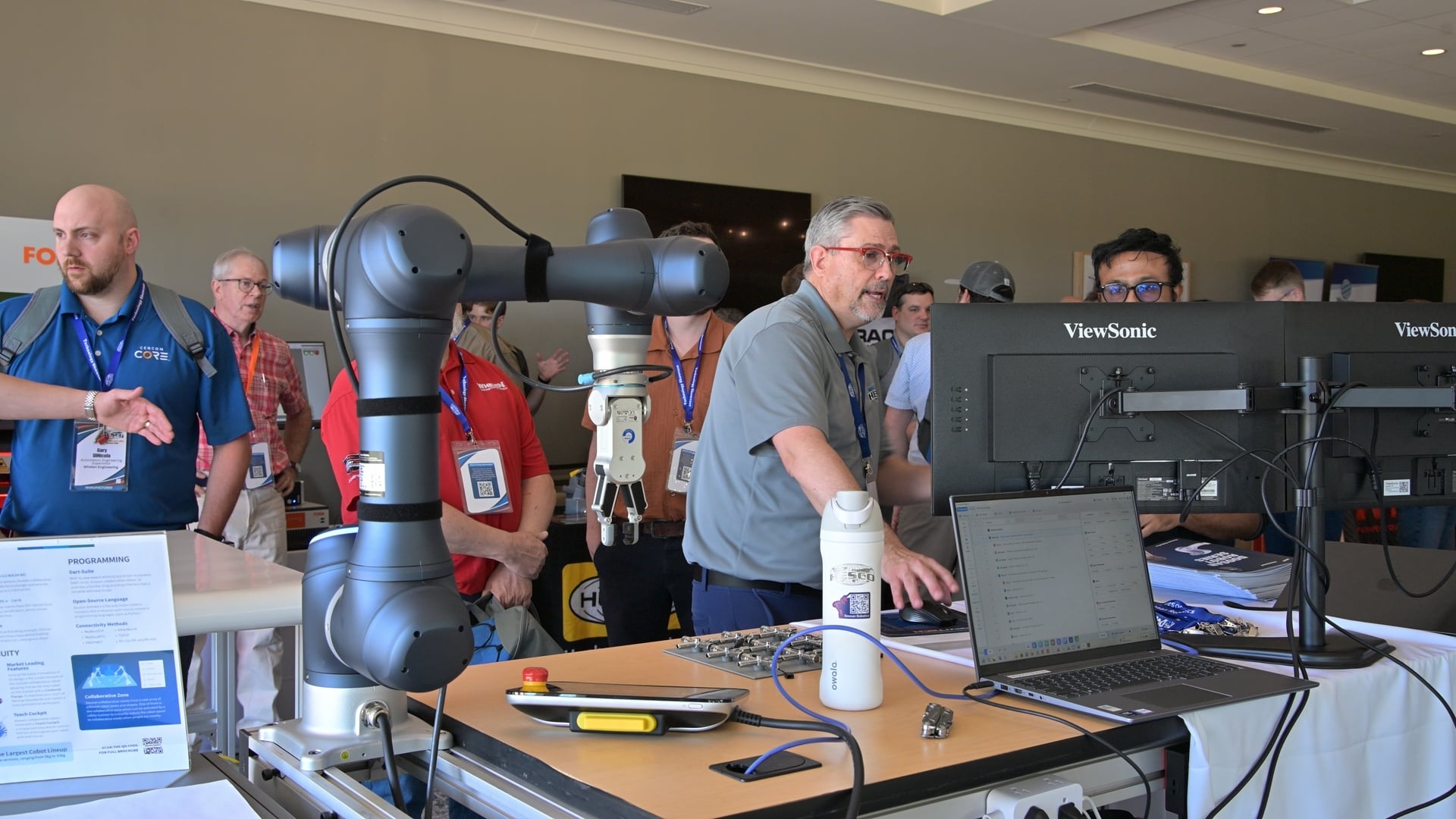 A Doosan collaborative robot arm with gripper draws a crowd at the HESCO Technology Showcase demo floor