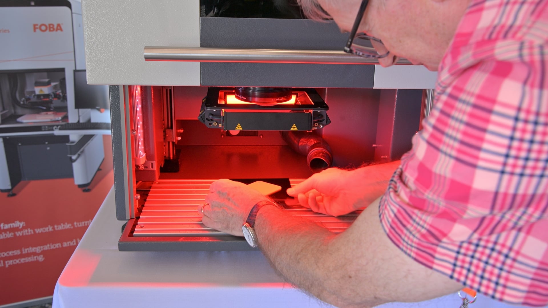 An attendee places a part into a FOBA laser marking system during a live demonstration at the HESCO Technology Showcase