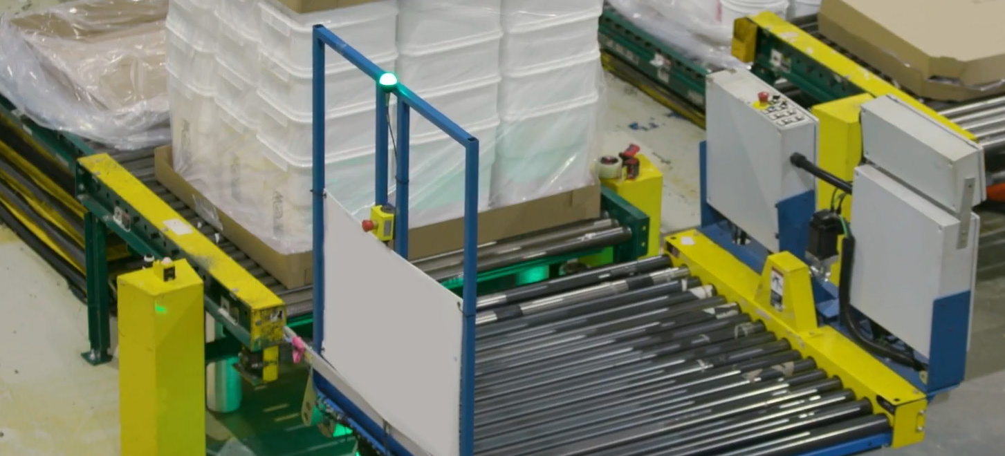 A conveyor attachment mid-transfer. The handoff — positioning, alignment, confirmation — is where the engineering sits.